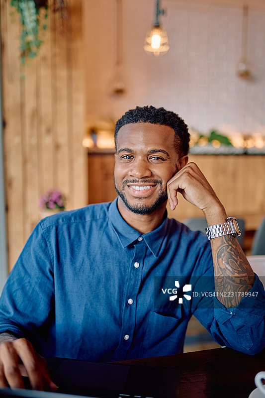 年轻的商人在咖啡馆里微笑着使用笔记本电脑工作图片素材