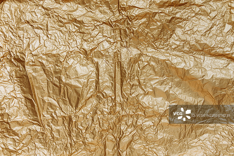 皱褶的金色纸张纹理背景，展示复杂的折叠和阴影，适合创意设计项目和艺术应用。图片素材