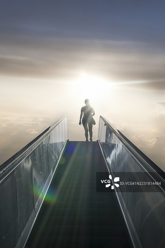 女人在日出时乘坐通往天空的自动扶梯。图片素材
