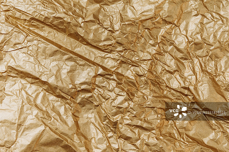皱褶的金色纸张纹理背景，展示了复杂的折叠和阴影，适合创意设计项目和艺术应用。图片素材