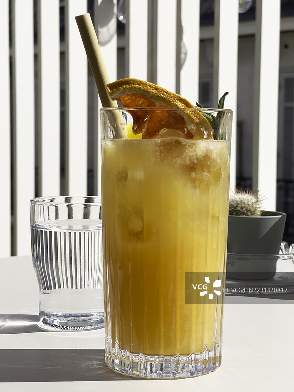桌子上摆放着一杯果汁鸡尾酒，背景是垂直的栏杆。图片素材