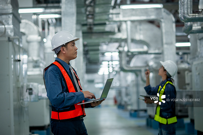 工程师或技术人员在处理大量金属管道、暖通空调系统和工业设备，暗示着一个受控、维护良好的环境概念。图片素材