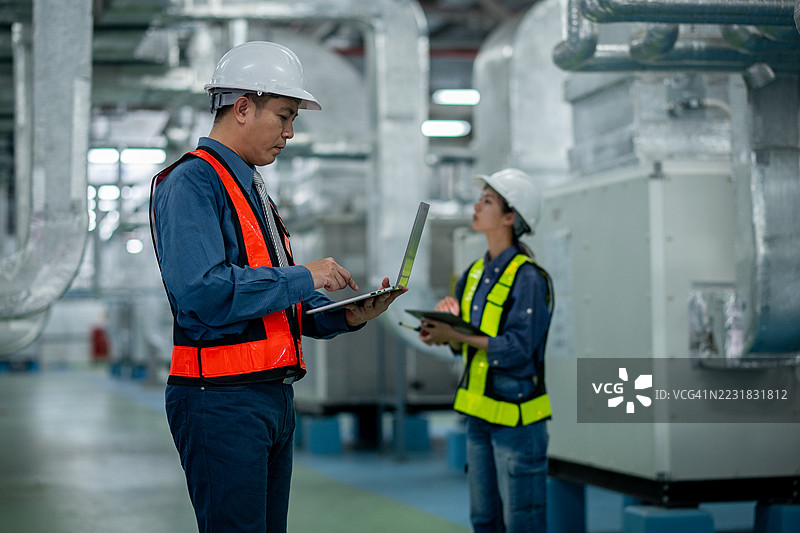 工程师或技术人员在处理大型金属管道、暖通空调系统和工业设备，暗示着一个受控且维护良好的环境概念。图片素材