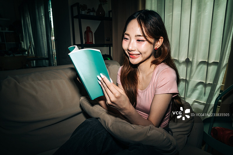 年轻女子在家微笑着阅读笔记本图片素材