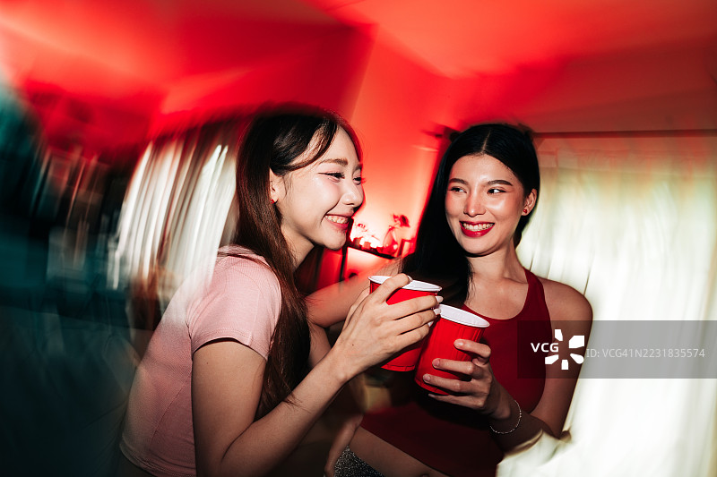 年轻女性享用饮品，伴有相机闪光灯和红光图片素材