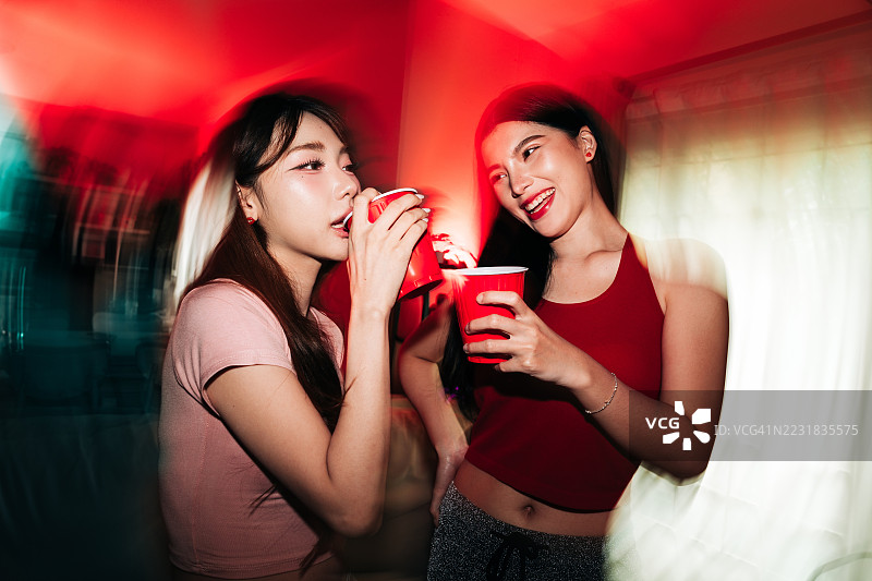 朋友们拿着红色杯子喝酒的抓拍派对闪光照图片素材