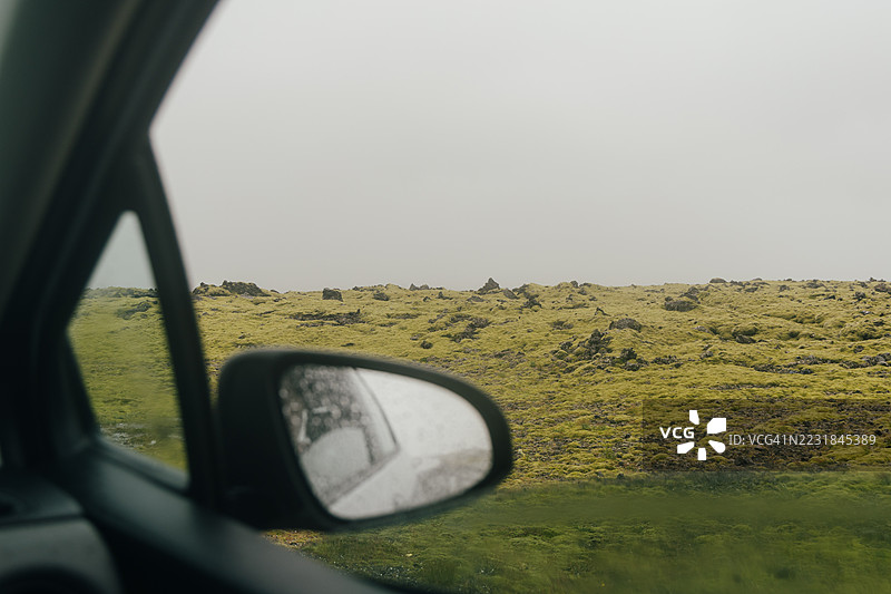 雨天透过车窗看到的冰岛苔藓覆盖的熔岩地貌图片素材