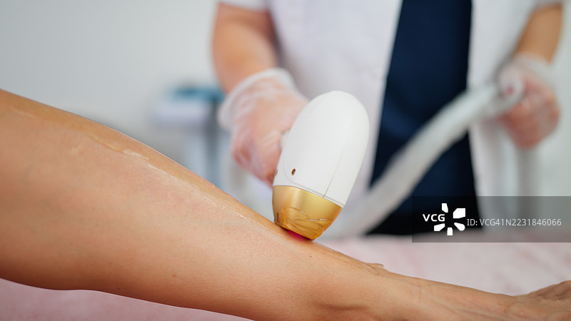 美容师使用激光脱毛仪为女性去除腿部毛发图片素材