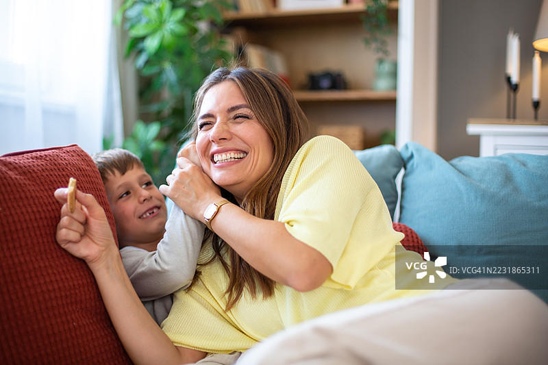 母亲和儿子在家里的沙发上欢笑玩耍图片素材