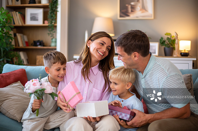 快乐的家庭在家庆祝母亲节，赠送礼物和鲜花图片素材