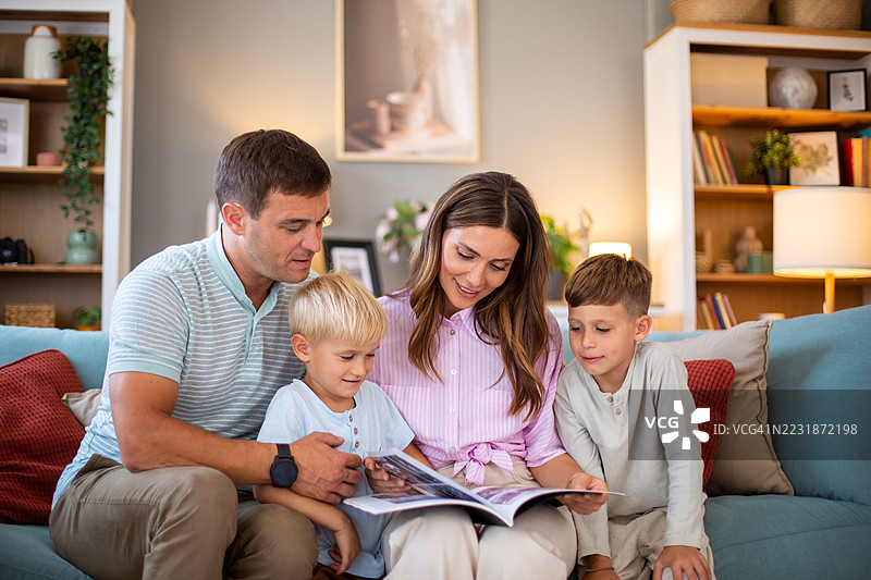一家人在家沙发上一起阅读一本书图片素材