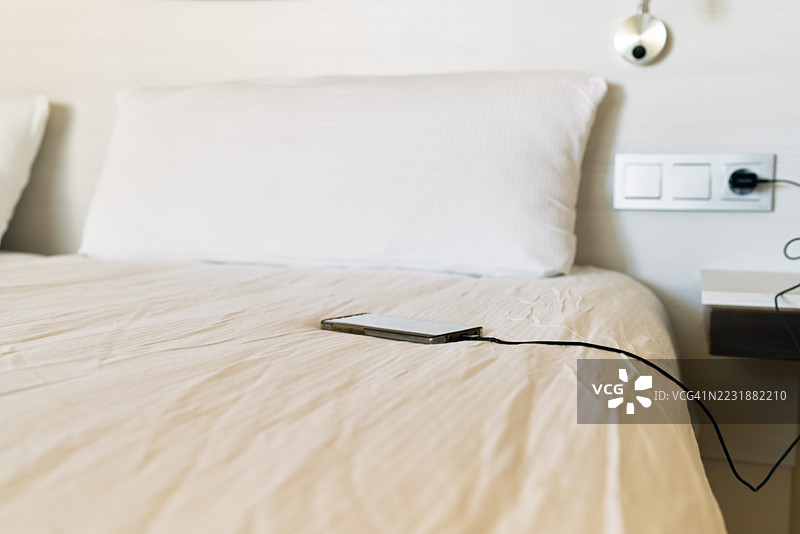 酒店房间床上充电的智能手机图片素材
