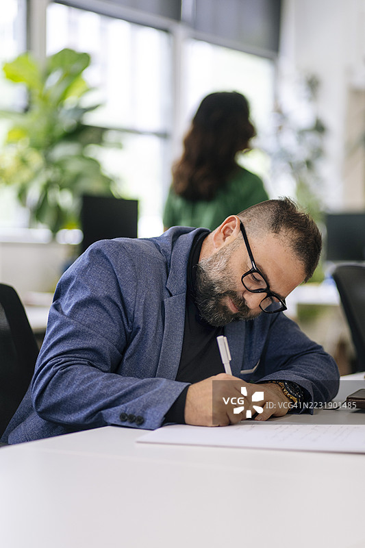 专注的男人在办公室工作区写作图片素材