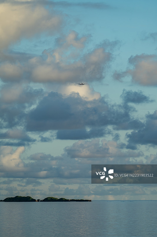 在日本冲绳的日落海滩上空飞行的飞机图片素材
