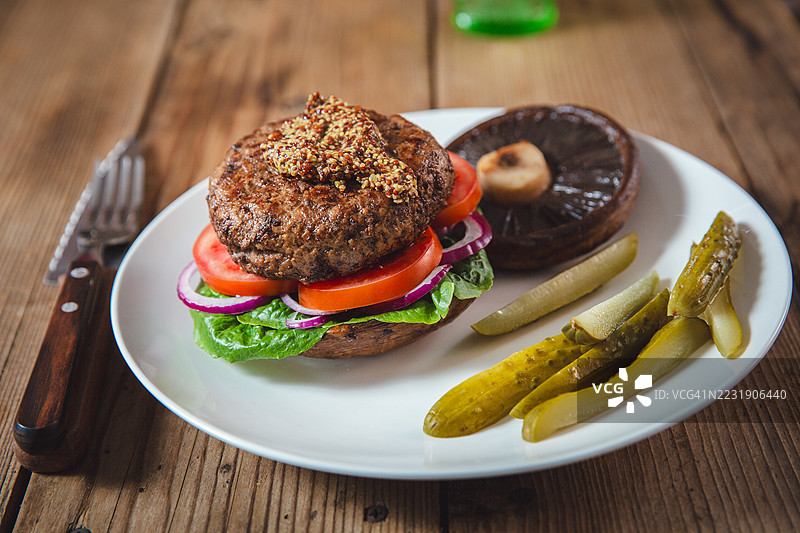 健康美味的牛肉汉堡，搭配新鲜蔬菜，放在乡村风格的盘子上图片素材