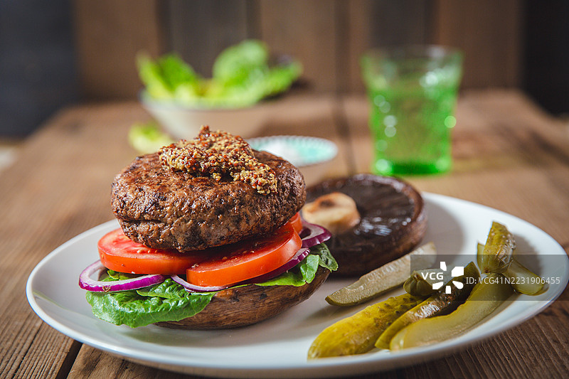 美味的波多贝罗火鸡汉堡，搭配腌黄瓜和绿叶，摆放在乡村风格的环境中图片素材