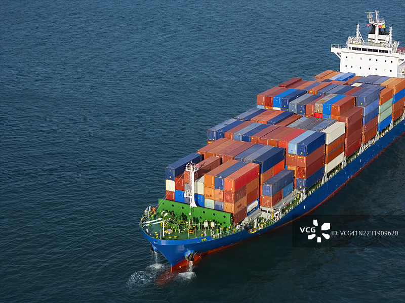 航拍视角的集装箱货船，满载集装箱，从商业港口的码头出发，适用于商业物流、进出口、航运或货物运输。图片素材