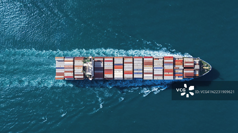 航拍视角的集装箱货船，满载集装箱，从商业港口的码头出发，适用于商业物流、进出口、运输或货运。图片素材