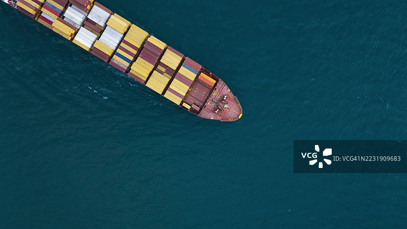 航拍视角的集装箱货船，满载集装箱，从商业港口的码头出发，适用于商业物流、进出口、运输或货运。图片素材
