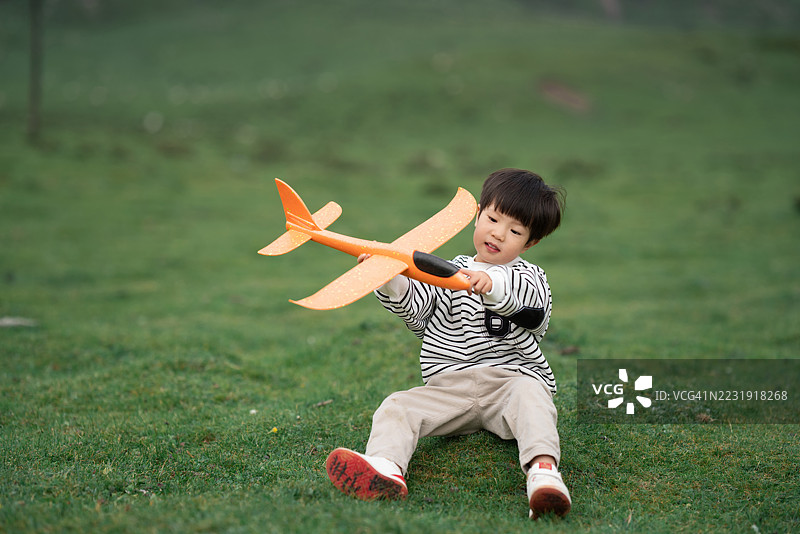 亚洲三岁儿童在草地上玩飞机模型图片素材