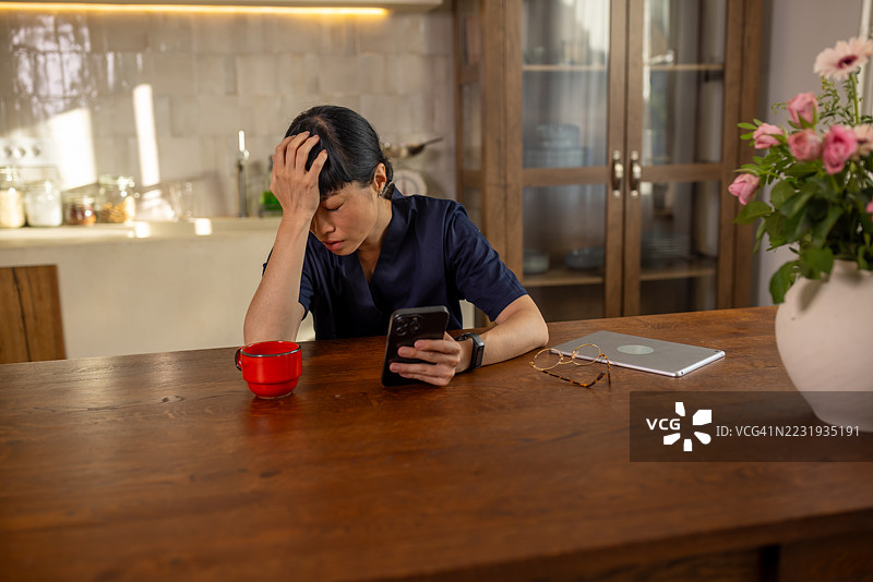 疲惫的女医生在家中使用智能手机图片素材