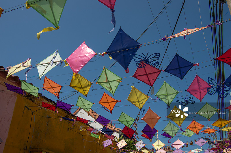 彩色风筝和蝴蝶剪纸装饰在哥伦比亚玻利瓦尔省卡塔赫纳德印第亚斯盖特塞马尼街区上空悬挂。图片素材