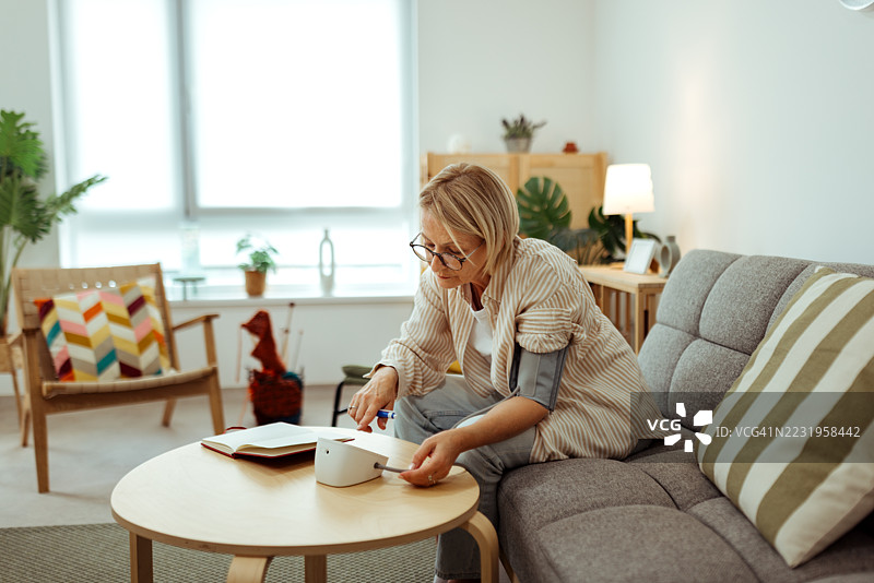 担心的女性在家中测量血压图片素材