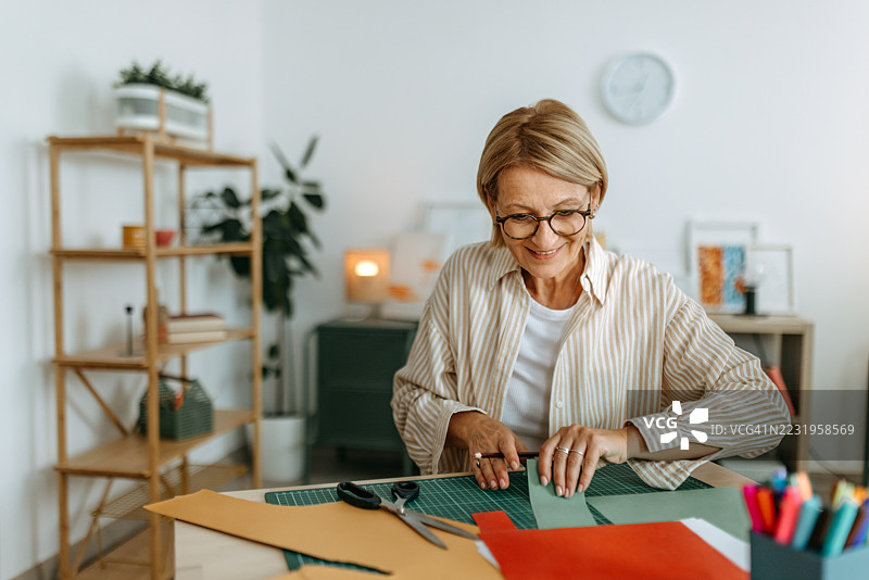 成熟的女性在家中进行多彩的纸艺手工制作图片素材