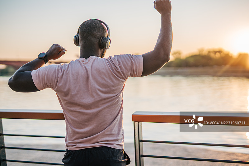 年轻运动员在日落时分听音乐庆祝成功图片素材