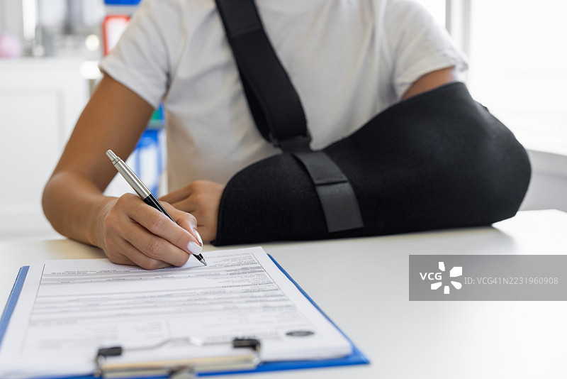 手臂骨折的女性正在填写表格图片素材