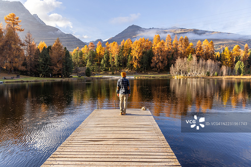 男人站在码头上俯瞰秋季湖泊图片素材