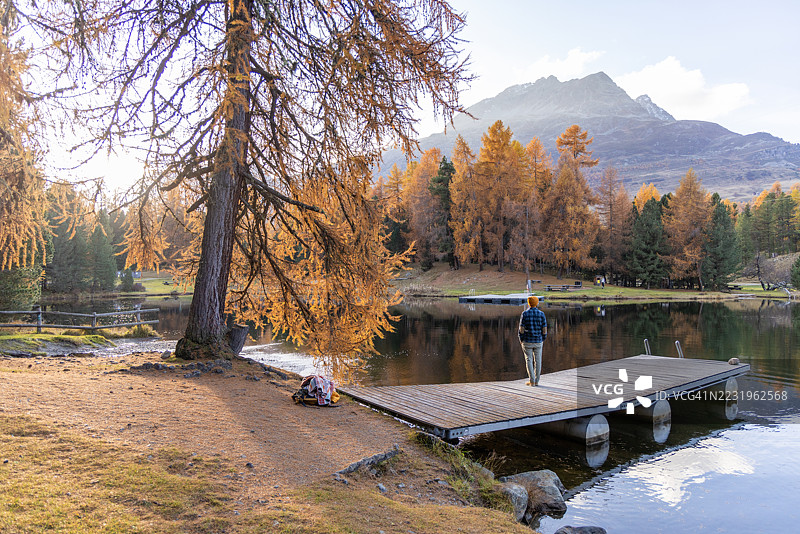 男人站在码头上俯瞰秋天的湖泊图片素材