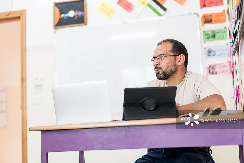 教室里坐在桌子上的男老师图片素材