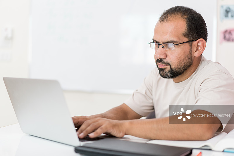 教室里坐在桌子上的男老师图片素材