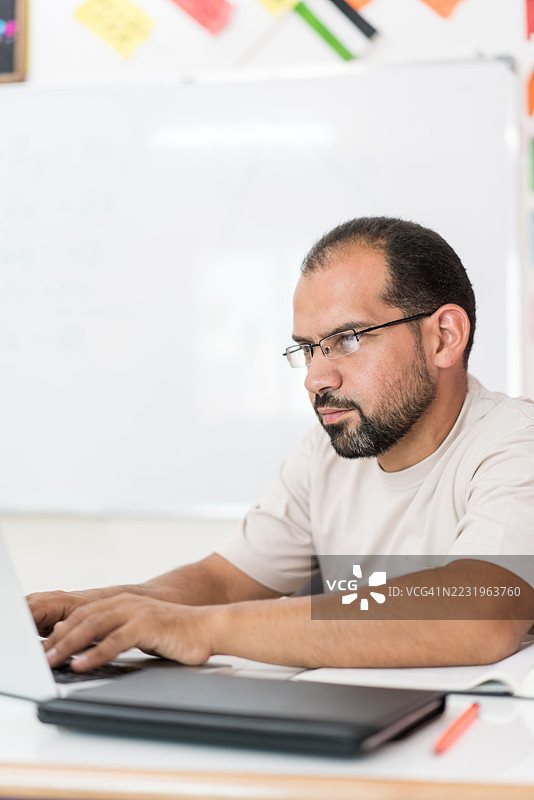 教室里坐在桌子上的男老师图片素材