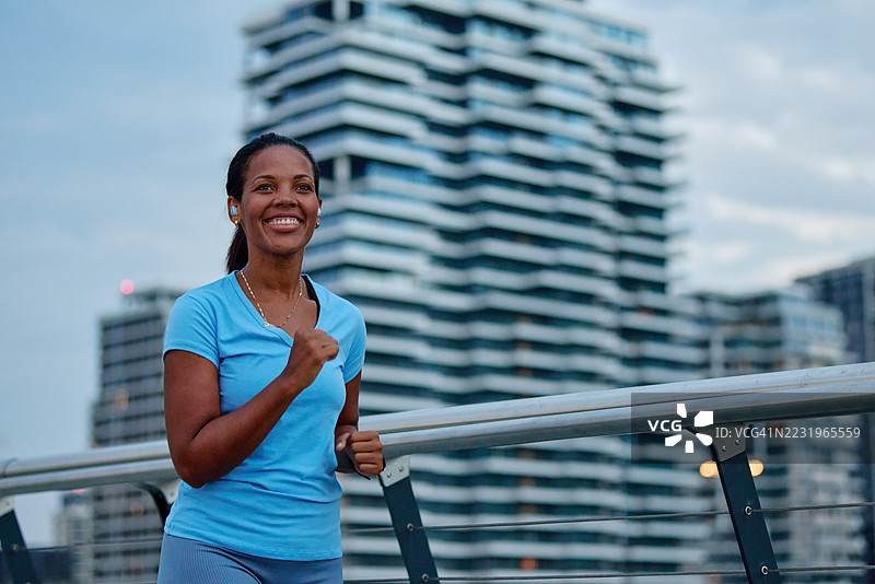 微笑的女性在日落时分于城市中奔跑图片素材