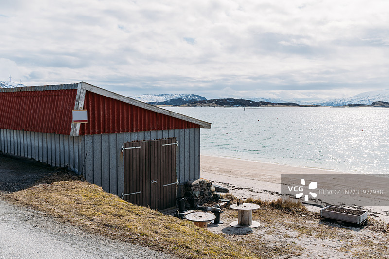 海岸小屋坐落在岩石海岸，背景是雪山图片素材