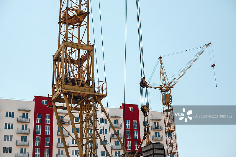 新建筑旁的施工起重机与蓝天白云相映成趣。图片素材