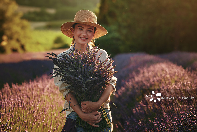 女人在日落时分的田野中手捧薰衣草花束图片素材