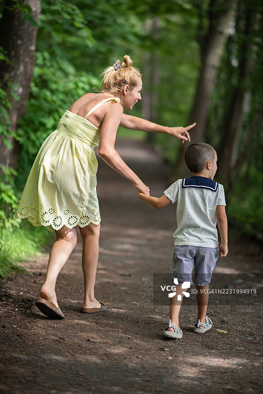 金发女性在森林里向她的小男孩展示某样东西。图片素材