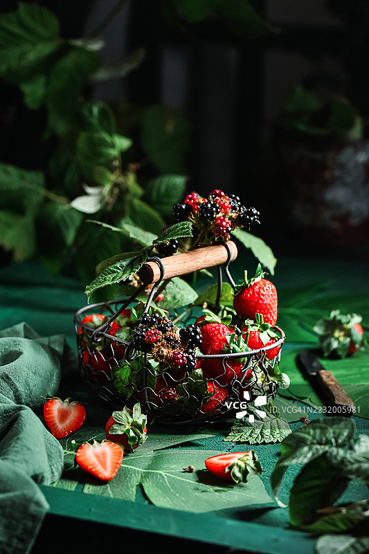 绿色桌子上的新鲜草莓和黑莓篮子图片素材