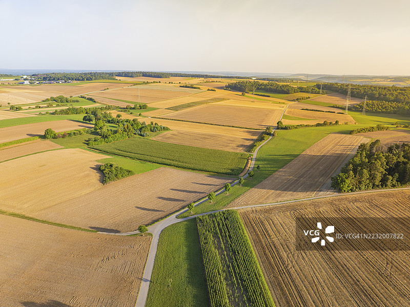 从高处俯瞰德国杰廷根的乡村景色，田野和蜿蜒的乡间小路穿过起伏的山丘。图片素材