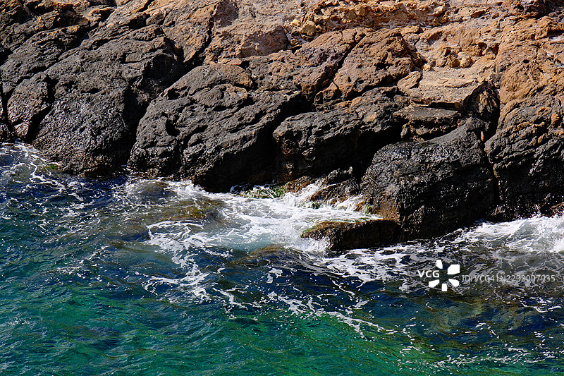 高角度视图的岩石海岸线，海浪拍打而来图片素材