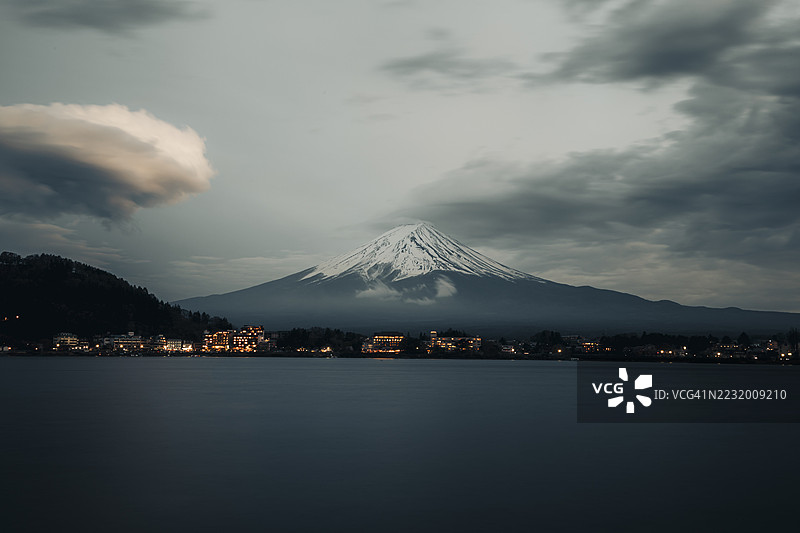 富士山的壮丽景色，黄昏时分宁静的湖泊和灯火辉煌的小镇， 日本图片素材