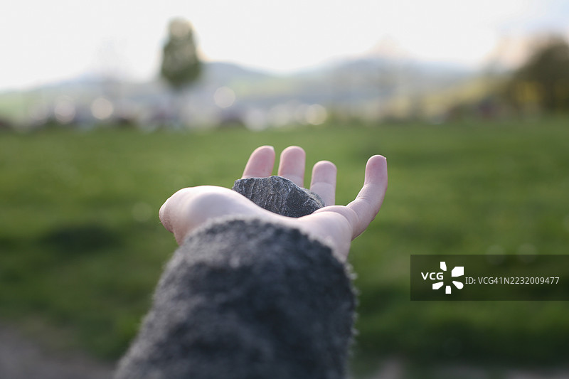手握石头在绿色田野中图片素材