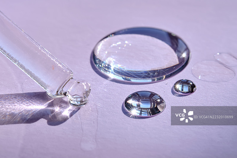 紫色表面上的滴管和液体水滴特写图片素材