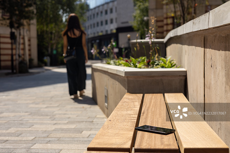 一位年轻的职业女性在英国欧洲布里斯托尔市中心行走时不小心掉落了她的智能手机图片素材