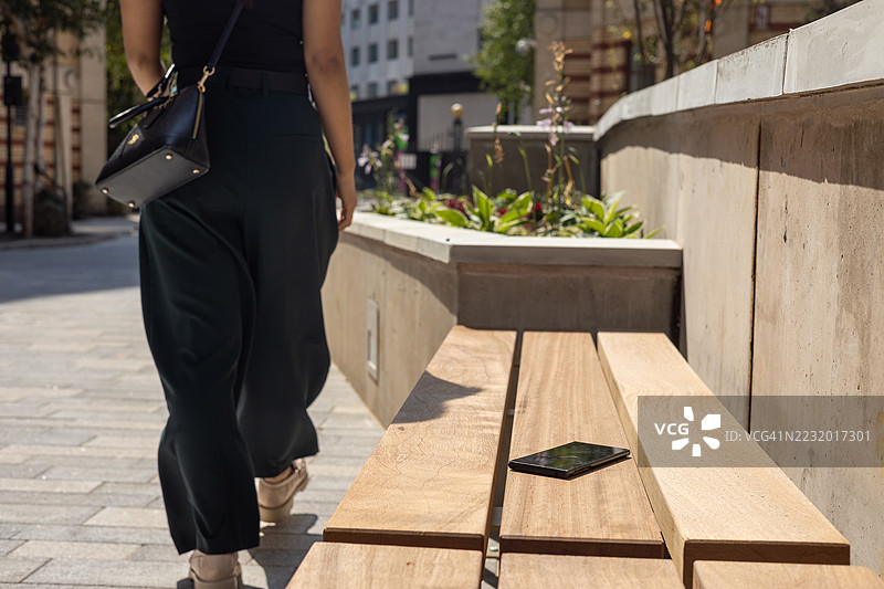 一位年轻的女商人走在英国欧洲布里斯托尔市中心时，不小心掉落了她的智能手机图片素材