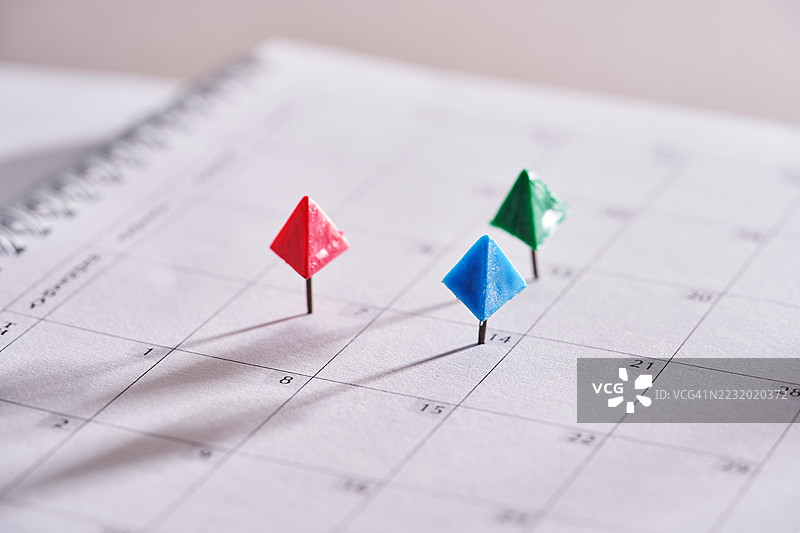 白色日历上用彩色图钉标记重要日期。图片素材