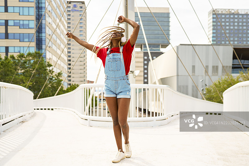 年轻女性在桥上跳舞并听音乐图片素材